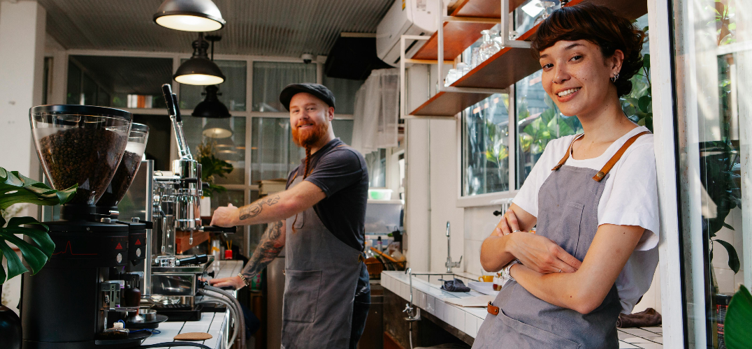 Man making coffee with a waitress smiling.