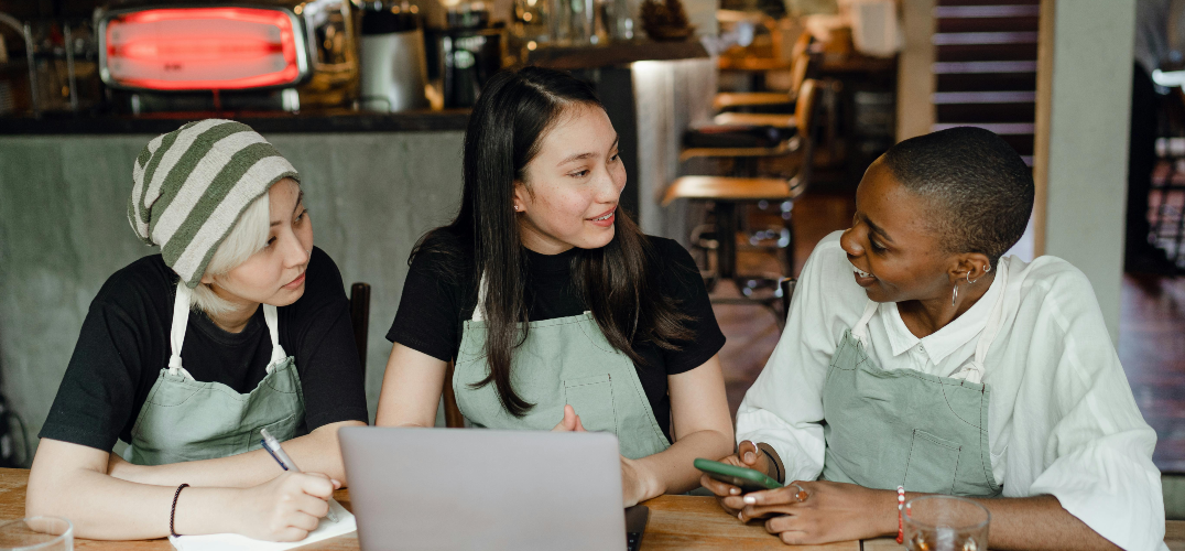 Friendly young diverse waitresses chatting during work in a cafe.